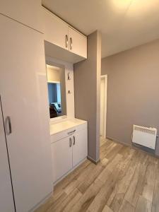 an empty kitchen with white cabinets and wood floors at Apartman Enigma II in Ruma +6 photos