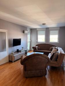 a living room with two couches and a flat screen tv at Apartman Enigma II in Ruma