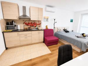 a kitchen and a bedroom with a bed and a purple chair at Honey Apartment in Moravske-Toplice +16 photos