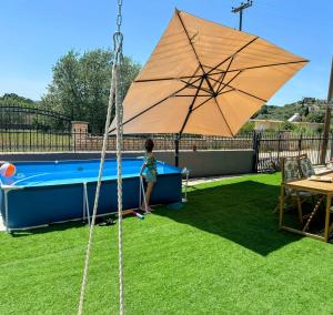 a child standing under a large umbrella next to a pool at Zen Stay Maisonette in Igoumenitsa