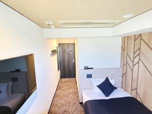 a bedroom with a bed with a blue pillow on it at HOTEL LiVEMAX BUDGET Nippori in Tokyo