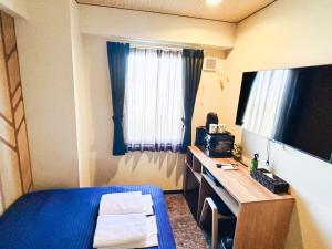 a room with a bed and a desk and a television at HOTEL LiVEMAX BUDGET Nippori in Tokyo