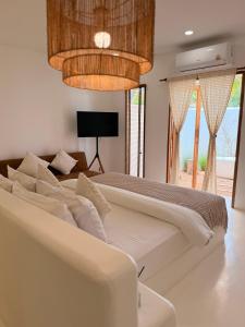 a white bedroom with a large bed and a chandelier at Kamari Cafe&Resort Kohlarn คามารีคาเฟ่แอนด์รีสอร์ทเกาะล้าน in Ko Larn