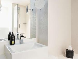 a white bathroom with a sink and a mirror at Adagio Paris 19ème Cité de la Musique in Paris