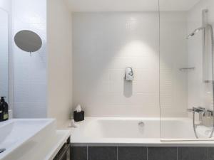 a white bathroom with a tub and a sink at Adagio Paris 19ème Cité de la Musique in Paris +18 photos