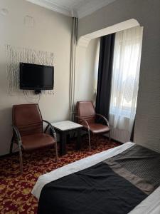 a hotel room with two chairs and a tv and a bed at Antik Otel in Ankara