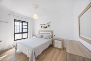 a white bedroom with a bed and a window at Casapoley Vejer in Vejer de la Frontera
