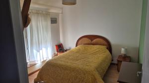 a bedroom with a bed with a yellow bedspread and a window at Biloba in Saint-Paul-lès-Dax