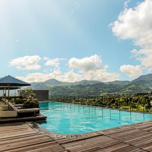 a large swimming pool with mountains in the background at The Botanica Sanctuary in Puncak