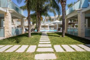 a walkway in front of a building with palm trees at Pietra Bianca Marzamemi in Marzamemi