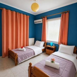 two beds in a room with blue walls and orange curtains at Sunset Apartments in Missolonghi