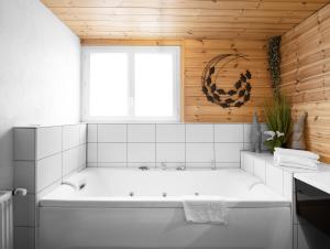 a white bath tub in a bathroom with a window at Logis Hôtel la Vigotte in Girmont-Val-dʼAjol +20 photos