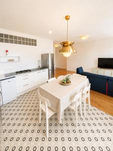 a kitchen and dining room with a white table and chairs at Galleria Massimo Trilocale Frontemare - Agenzia Cocal in Caorle +3 photos