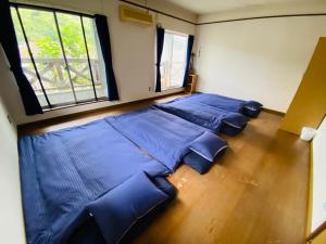 a large bed in a room with blue sheets at Guest House Rakufu in Anan