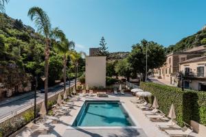 a swimming pool with chairs and umbrellas at Modica Inn Centro, BW Premier Collection in Modica