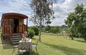 a table and chairs in a field with a tree at La roulotte à la ferme in Palogneux