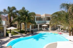 a large swimming pool in front of a building with palm trees at Pietra Bianca Marzamemi in Marzamemi