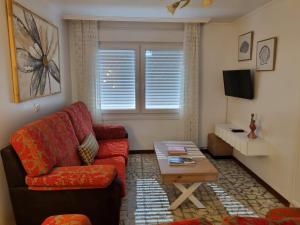 a living room with a red couch and a coffee table at O Curro de Arou in Arou