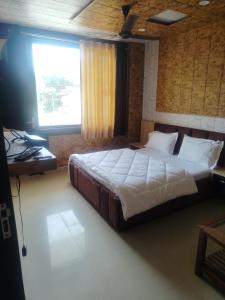 a bedroom with a bed and a desk and a window at New Vybent Hotel Kainchi Dham in Bhowāli