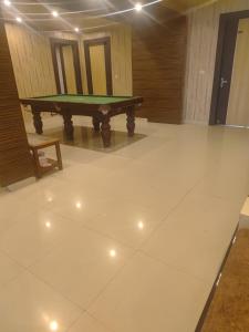 a ping pong table in a room with a white floor at New Vybent Hotel Kainchi Dham in Bhowāli