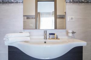 a white bathroom with a sink and a mirror at Pietra Bianca Rooms in Pachino