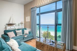 a living room with a blue couch and a large window at Porthminster Mews 2 in St Ives