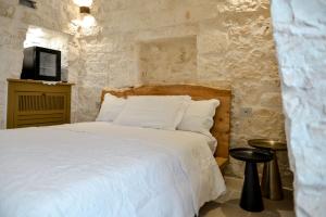 a bedroom with a white bed and a tv at Borgo Pascarosa in Ostuni +106 photos
