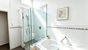 a bathroom with a glass shower and a tub at Clifftop Coastal Retreat with Ocean Views - Close to Beach & Cafés in Auckland +14 photos