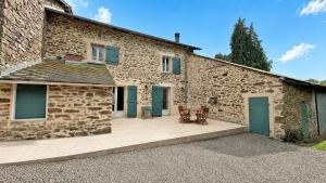a stone house with blue doors and a patio at La petite ecosse in Châteauneuf-la-Forêt