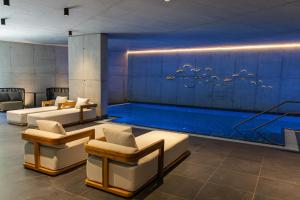a pool with couches and chairs in a room at Hotel Ráztoka in Trojanovice