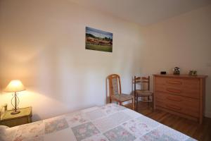 a bedroom with a bed and a dresser and a chair at La petite ecosse in Châteauneuf-la-Forêt