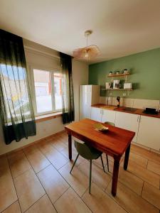 a kitchen with a wooden table and a kitchen with green walls at Le Temps d une Pause in Calais