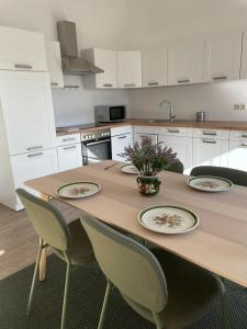 a kitchen with a wooden table with plates and chairs at Ferienwohung in Maissau in Maissau +5 photos