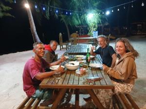 a group of people sitting at a picnic table at Fadhila Cottages Togean Dive Resort in Katupa +26 photos