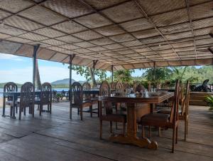 a dining room with a table and chairs on a deck at Fadhila Cottages Togean Dive Resort in Katupa