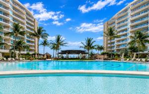 a large swimming pool with palm trees and buildings at Luxury Beachfront Condo at Del Canto Residences - Amazing Views! in Nuevo Vallarta