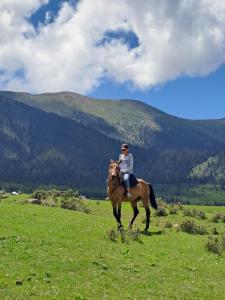 a person riding a horse in a field at "AILUN" Issyk Kul in Tong