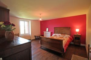 a bedroom with a red wall with a bed and a dresser at Boissac in Le Vigen