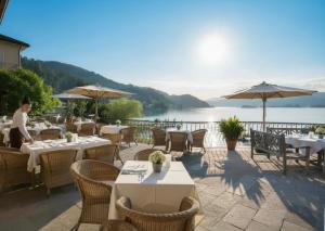 a restaurant with tables and chairs and a view of the water at Linde Villas in Maria Wörth
