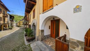an alley in a town with a wooden door at Hostdomus - Petit Bleu in Cesana Torinese