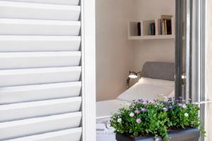 a room with a bed and a window with a pot of flowers at Vittorio Emanuele Apartment - Downtown Como in Como +6 photos