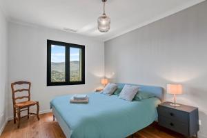 a bedroom with a blue bed and a chair at Les Oliviers De Lunéa in Fayence