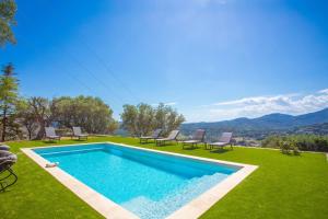 a swimming pool in the middle of a lawn with chairs at Les Oliviers De Lunéa in Fayence