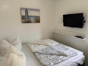 a bedroom with two pillows and a tv on the wall at Strandoase in Grömitz