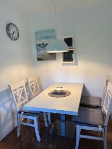 a white dining room table with chairs and a clock at Strandoase in Grömitz +6 photos