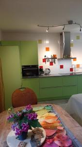 a kitchen with green cabinets and a table with flowers on it at BIESBOSCHBEST in Werkendam