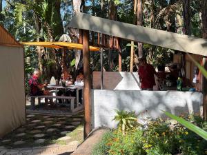 a group of people sitting at a table under an umbrella at Kholiwe 1 - 4 sleeper glamping in a forest in Port Edward