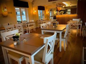 a restaurant with wooden tables and white chairs at Sea & Stay Bredene Zeewind 2 in Bredene
