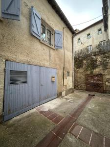 a building with a blue garage door and windows at La maison du Quart - Maison de village in Sommières
