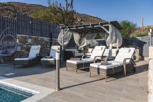 Eine Gruppe von Stühlen unter einem Sonnensegel neben einem Pool in der Unterkunft Villa Parisi Naxos Deluxe in Naxos Chora